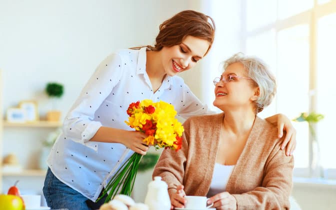 woman showing the flowers to senior woman